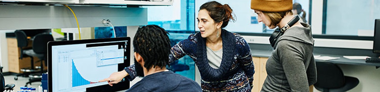 Three students looking at monitor